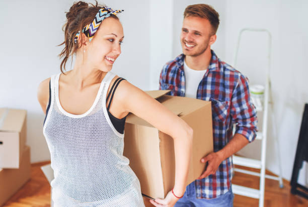 istock Couple carrying cardboard boxes, working together as a team 1302489075