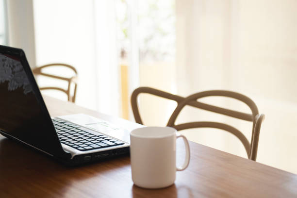 Photo of a laptop and cup of coffee over the table.