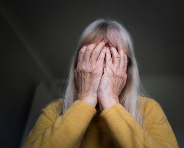 istock Depressed senior woman with hands over face at home 1302490101