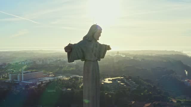 Aerial view around Sanctuary of Christ the King, Santuario de Cristo Rei and Lisbon city, Portugal. Drone footage at sunset. Catholic monument