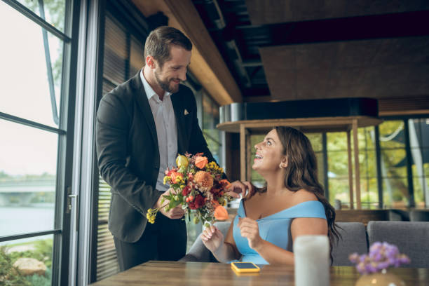 istock Woman sitting at table and standing man with bouquet 1302490608