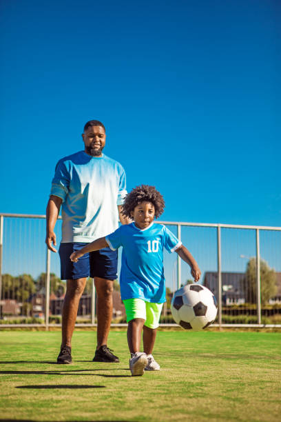 istock Black father and young son training on the football pitch 1302492017