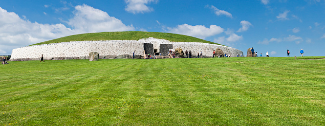 County Meath, Ireland - June 1, 2016. Panoramic shot of a group of tourists at Newgrange in County Meath, it was built during the Neolithic period, around 3200 BC.