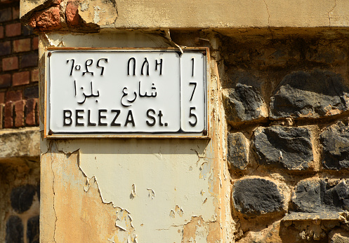 Asmara, Eritrea: tree languages and three scripts, Tigrinya - Arabic - English and Ge'ez (fidäl) - Arabic - Roman - street name on the Italian colonial building of the Banca Nazionale del Lavoro, Beleza Street (175th Street), former Via della Croce del Sud.