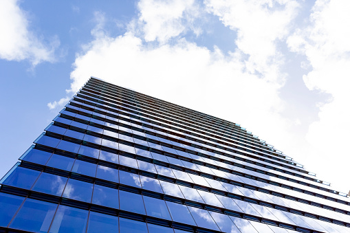 Low angle view of modern office building, skyscraper with reflection of sky, background with copy space, full frame horizontal composition