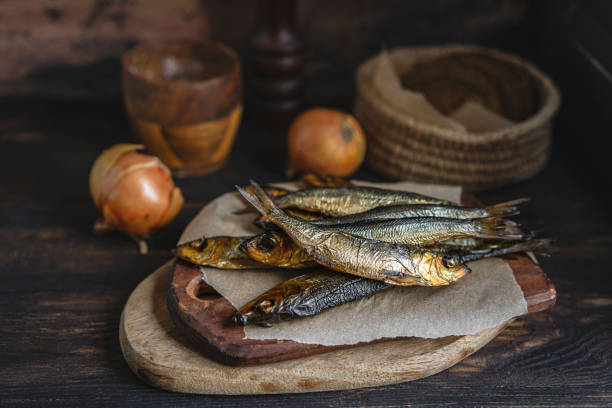 冷たいスモークニシンパン、タマネギは食べる準備ができています。暗い木製のテーブルの上に小さな黄金の魚のクローズアップ - prepared fish fish grilled close up ストックフォトと画像
