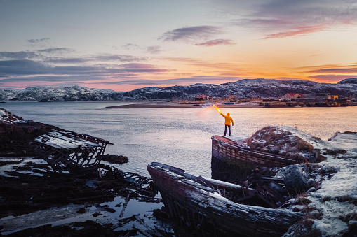 Russia, Teriberka, November,30 2020. A yellow figure with a signal light. Graveyard of ships, winter sunset view in an old fishing village on the shore of the Barents sea, the Kola Peninsula, Teriberka, Russia.