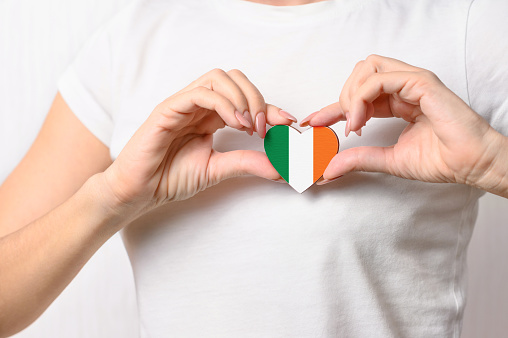 Love Ireland. The girl holds a heart in the form of the flag of Ireland on her chest. Irish patriotism concept