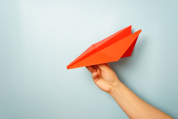 istock A woman's hand holds a red paper airplane on a pale blue background 1302499297