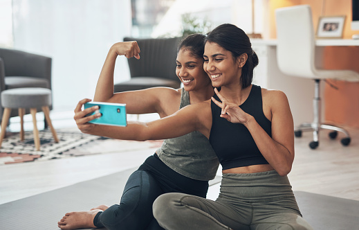 Shot of two young women taking a selfie while sitting at home in exercise clothes