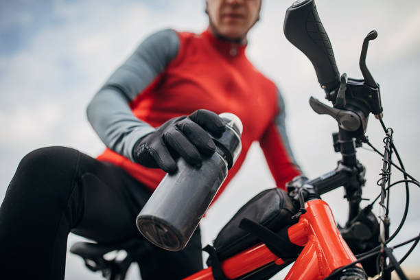 One man, professional male cyclist riding taking a water bottle from bicycle on road.