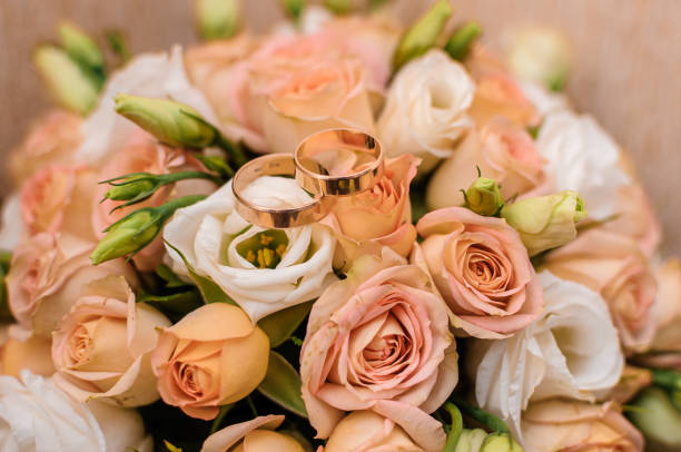istock Bridal bouquet with orange roses. Gold wedding rings 1302500800