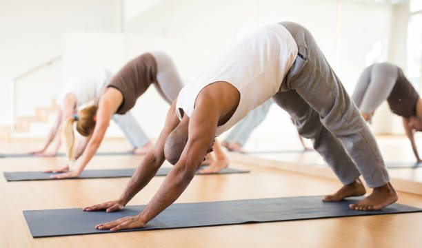istock Man making yoga exercises at group class 1302501226