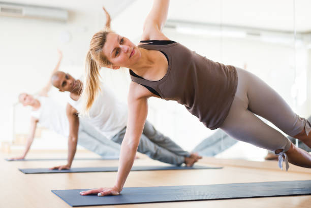 istock Woman standing in balancing pose Vasisthasana during group yoga training 1302501252