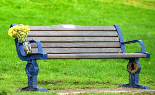 Wooden bench with a bunch of flowers left on it in memory of someone