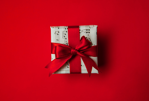 The gift box covered with musical note paper on red background.