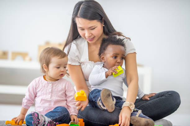 istock Asian female preschool teacher playing with her students 1302502813