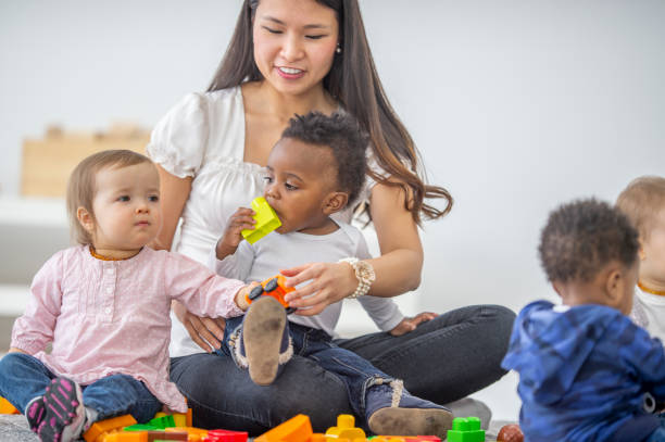 istock Asian female preschool teacher playing with her students 1302503326