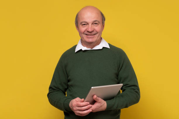 istock Elegant senior bald man smiling confident at camera holding a tablet 1302504656