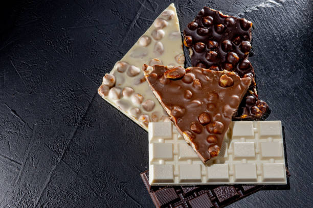 istock Three types of chocolate - black, milk and white on a black background with copy space 1302504731