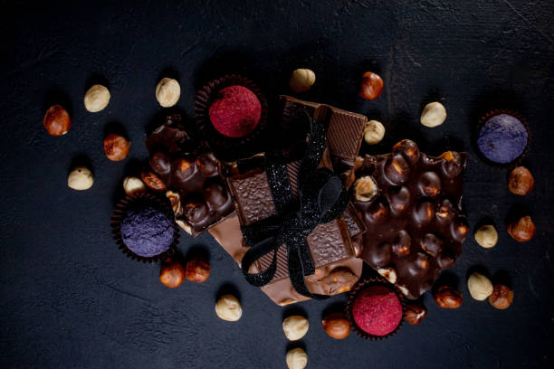 istock Chocolate candy truffle with chocolate pieces and flying cocoa powder on a dark background 1302504813