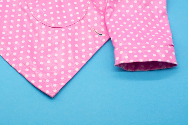 Children's pink raincoat with polka dots on a blue background.
