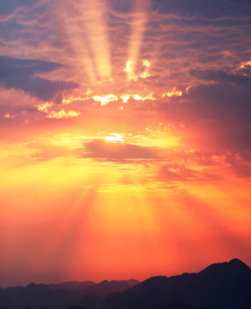 Sunset and sunrise against the beautiful clouds of red purple and pink with bright hot rays symbolize the beginning of a new day, good and peace