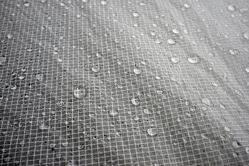 Beautiful round rain dew water drops are collected on the silicone water-repellent hydrophobic fabric of the tent