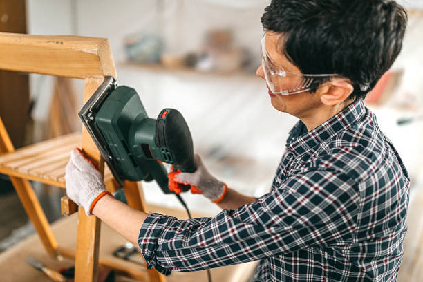 istock Woman sanding wooden chair using electric sanding hand machine 1302506083