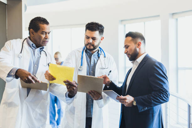 istock Three male doctors confer about test results 1302507391