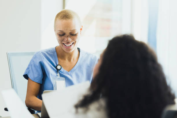 istock Mid adult nurse smiles while typing notes on laptop 1302507423