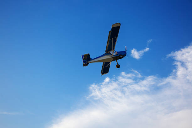 Small private plane climbs through the clouds. Small private plane climbs through the clouds. Fliyng ultralight aircraft across the blue sky. Copy space. ultralight photos stock pictures, royalty-free photos & images