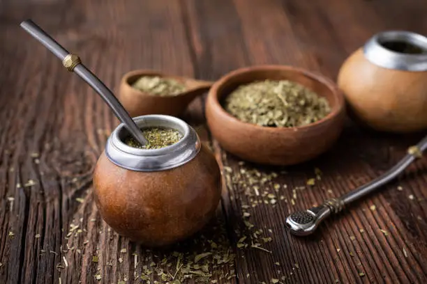 Healthy infused drink, classic Yerba Mate tea in a gourd with mobilla on wooden background