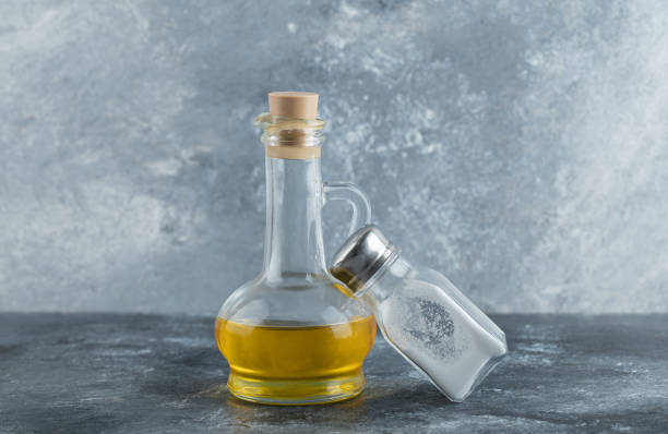 istock Bottle of oil and salt on grey background 1302511721