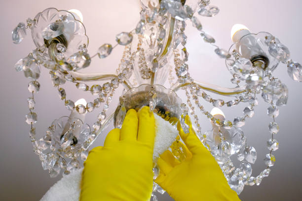 Close-up of gloved hands wipes dust from the chandelier. House cleaning. Close-up of gloved hands wipes dust from the chandelier. House cleaning. chandelier earring stock pictures, royalty-free photos & images