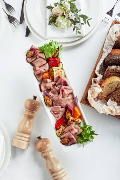 Sliced Beef or Pork with Marinated Vegetables and Sauce. Beautifully decorated catering banquet menu. Food snacks and appetizers for buffet on white background
