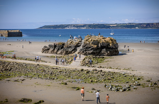 25 July 2018: Marazion, Cornwall, UK-Tourists walk along the beaches of Marazion, an ancient market town in Cornwall, England.