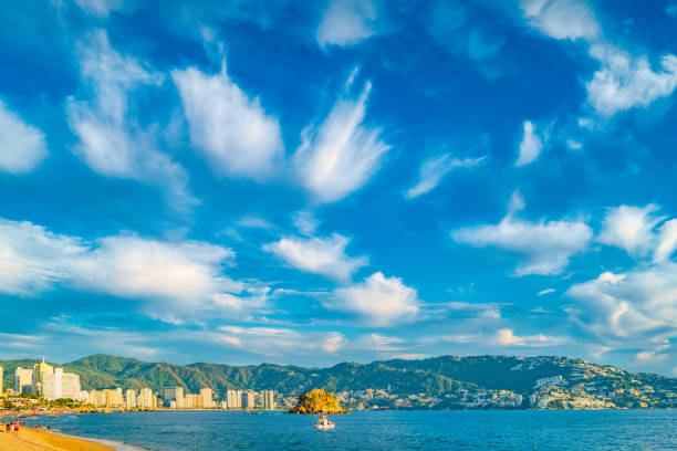 Acapulco, Mexico - November 25, 2008: Exit of blue water bay with Cabo Marques making start of Pacific Ocean. Blue sky. Green hills with few buildings.