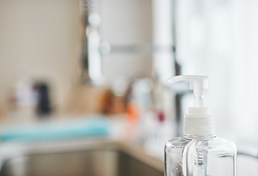 Liquid soap or antibacterial hand sanitizer dispenser next to kitchen sink and faucet