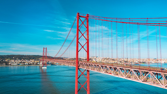 Aerial view or drone photo of the 25 De April Bridge. Red bridge is connecting Lisbon and Almada across the river Tagus. Lisbon and Portugal sightseeing. High quality photo