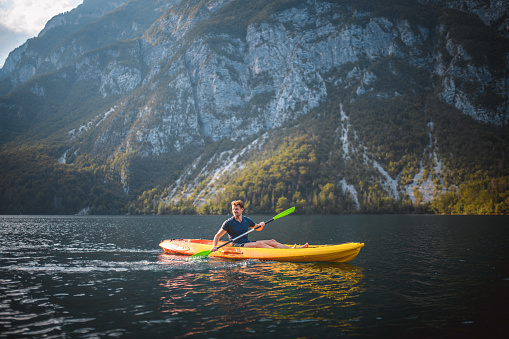 Smiling Caucasian male kayaker paddling on Lake Bohinj while enjoying vacation in Triglav National Park, Slovenia.