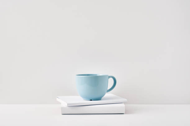 istock The mug stands on a stack of books on a white background. Natural and eco-friendly materials. Copy space, mock up 1302532524