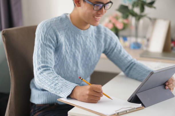 istock asian young student man entrepreneur working with tablet studying learning online at home. e-learning webinar meeting. social distance in covid pandemic 1302532897