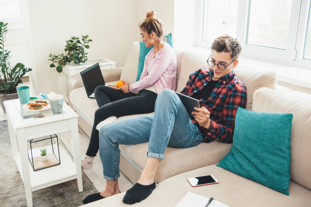 istock Caucasian couple at home sitting in bed and working from the computer while drinking a tea with sandwiches 1302537776
