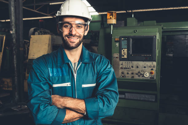 junge geschickte fabrikarbeiter oder ingenieur nahaufnahme porträt in der fabrik - manual worker portrait helmet technology stock-fotos und bilder