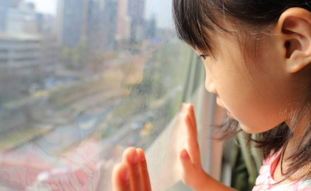 istock a Asian girl watching through glass window. 1302547572