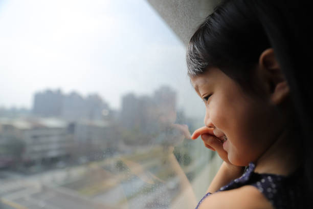 istock a Asian girl watching through glass window. 1302547586