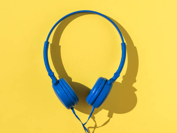 istock Blue headphones in bright light on a yellow background. 1302548200