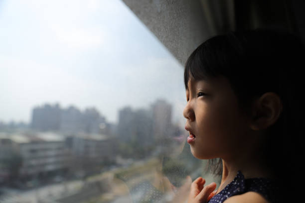 a Asian girl watching the city building through glass window.