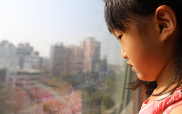 istock a Asian girl watching through glass window. 1302548300